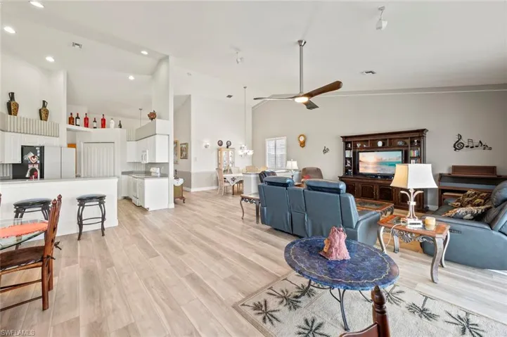 Living room with ceiling fan, high vaulted ceiling, and light hardwood / wood-style floors
