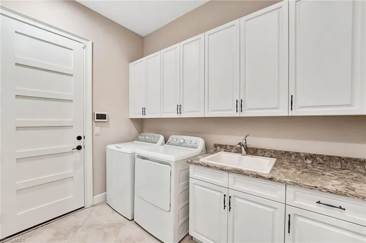 Laundry room featuring cabinet space, independent washer and dryer, and light tile patterned floors