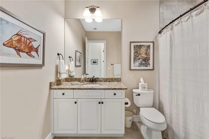 Bathroom featuring curtained shower, vanity, and light tile patterned flooring