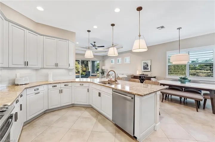 Kitchen with hanging light fixtures, light stone countertops, stainless steel appliances, and recessed lighting