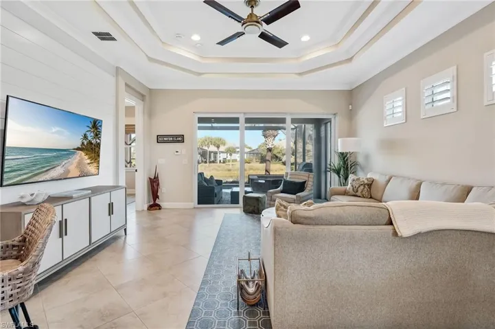 Living area with ceiling fan, light tile patterned floors, crown molding, a tray ceiling, and recessed lighting