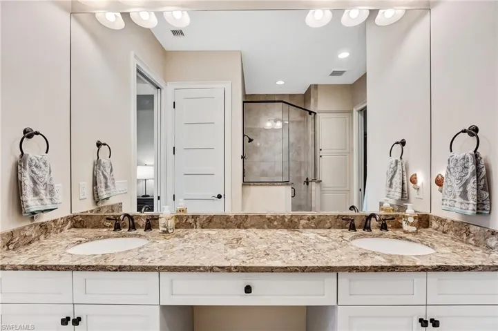 Bathroom featuring double vanity and a shower stall