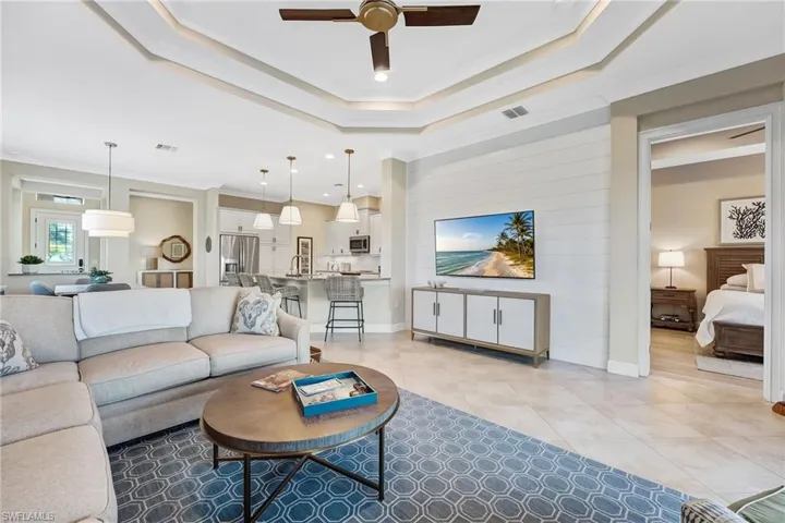 Living room featuring ornamental molding, ceiling fan, a tray ceiling, and light tile patterned floors