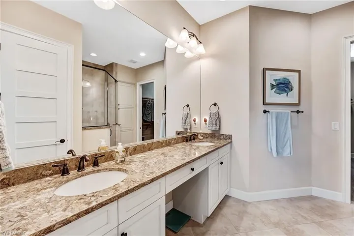 Full bathroom featuring double vanity, a walk in closet, and light tile patterned floors