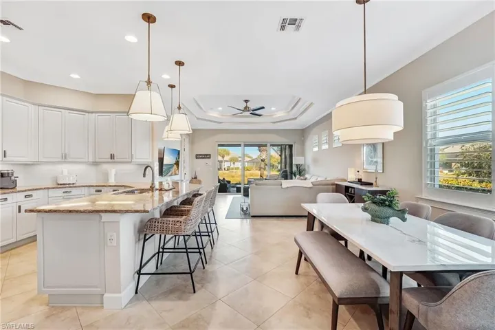 Kitchen with decorative light fixtures, light stone countertops, open floor plan, a ceiling fan, and tasteful backsplash