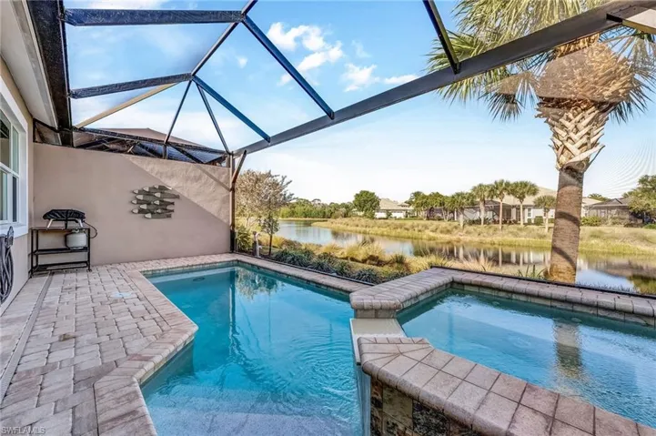 View of swimming pool with a lanai, a patio area, a water view, a sunroom, and a pool with connected hot tub