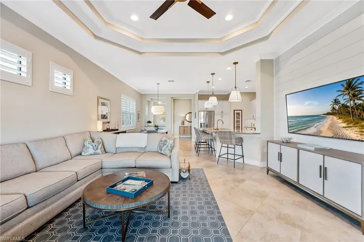 Living area with crown molding, ceiling fan, a tray ceiling, recessed lighting, and light tile patterned flooring