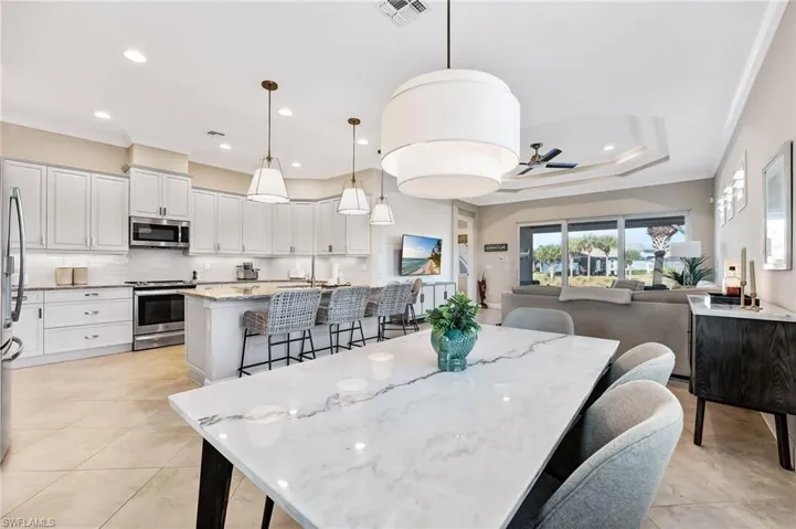 Dining area with ornamental molding, ceiling fan, light tile patterned floors, recessed lighting, and a tray ceiling