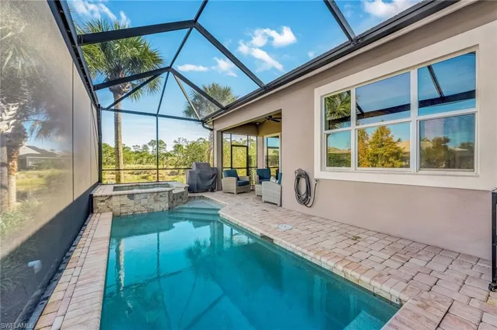 View of pool with a sunroom, a patio area, and glass enclosure