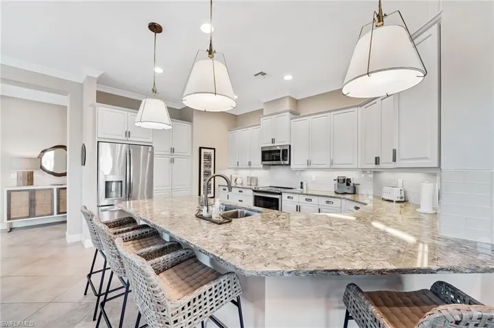 Kitchen featuring a breakfast bar, a peninsula, tasteful backsplash, stainless steel appliances, and white cabinets