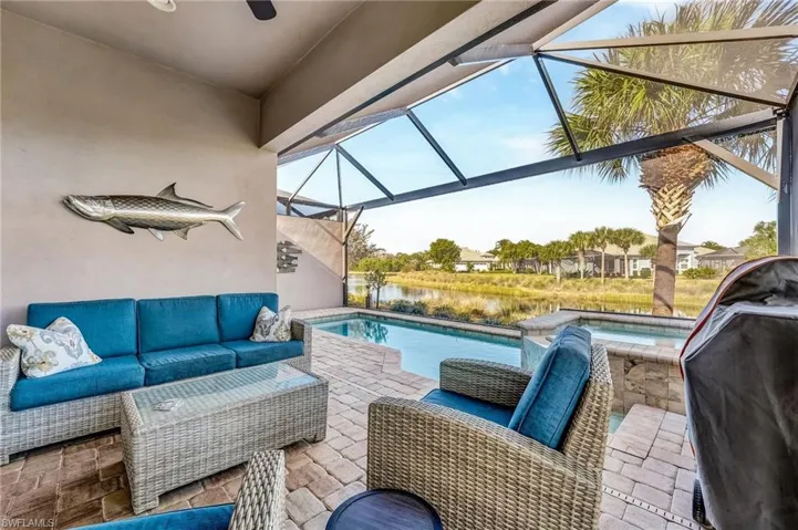 View of patio featuring a lanai, a sunroom, area for grilling, an outdoor hangout area, and a water view