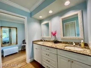 Full bath featuring radiator, double vanity, ornamental molding, light wood-type flooring, and recessed lighting