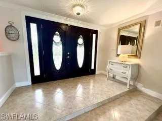 Entrance foyer with crown molding and light tile patterned flooring