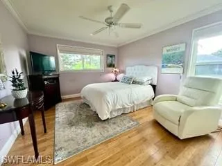 Bedroom featuring light wood finished floors, crown molding, and ceiling fan