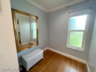 Spare room featuring wood-type flooring and crown molding