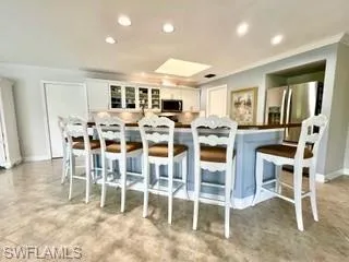 Kitchen with glass insert cabinets, a kitchen bar, stainless steel appliances, recessed lighting, and white cabinets