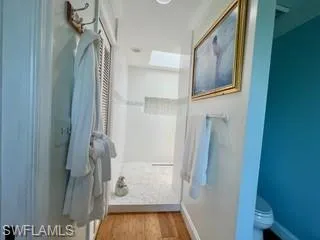 Bathroom with a stall shower, light wood-style flooring, and a skylight