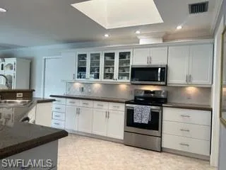 Kitchen featuring tasteful backsplash, glass insert cabinets, stainless steel appliances, crown molding, and white cabinets
