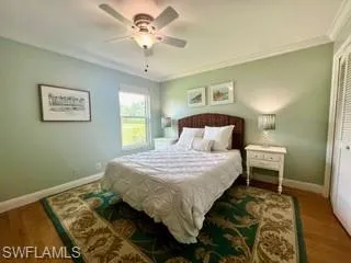 Bedroom with crown molding, wood finished floors, a ceiling fan, and a closet