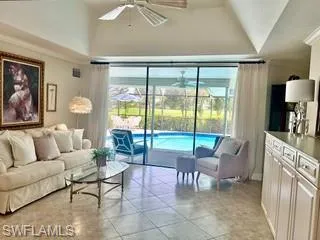 Living room featuring ceiling fan, light tile patterned floors, a sunroom, and high vaulted ceiling