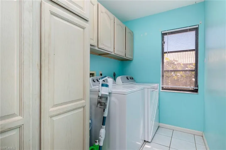 Laundry area featuring cabinets, light tile patterned floors, and independent washer and dryer