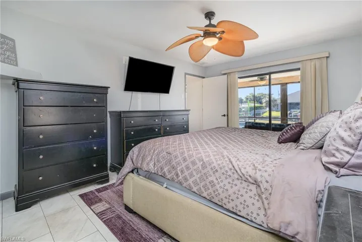 Tiled bedroom with ceiling fan and access to exterior