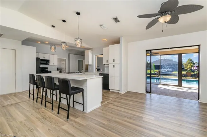 Kitchen with decorative light fixtures, vaulted ceiling, black appliances, and white cabinets