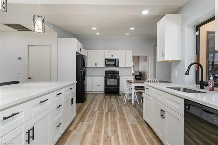Kitchen featuring pendant lighting, sink, black appliances, and white cabinets
