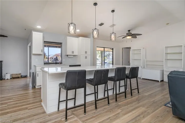 Kitchen featuring decorative light fixtures, a center island, and white cabinets