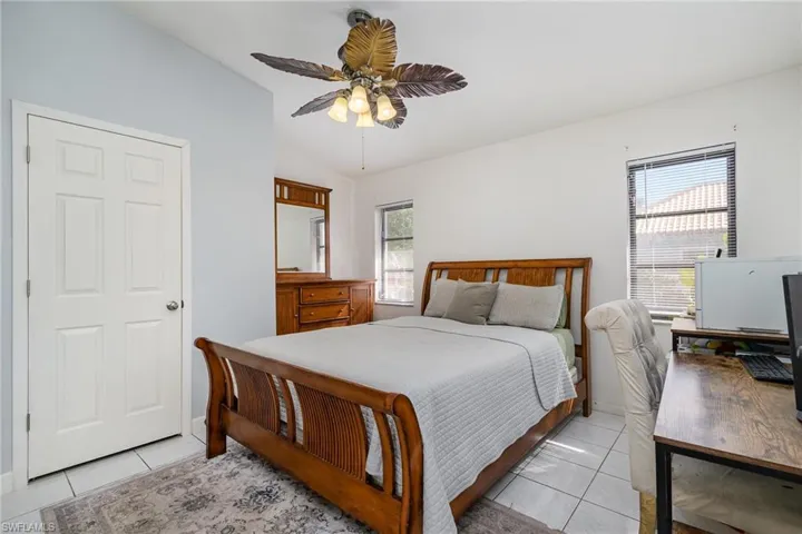Tiled bedroom featuring lofted ceiling, multiple windows, and ceiling fan