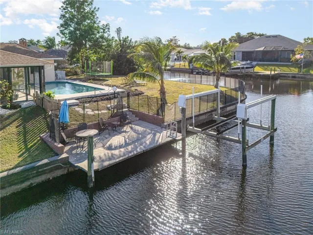 View of dock featuring a water view, a patio area, and a lawn