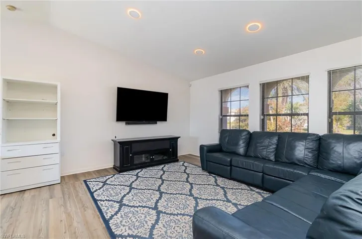 Living room with vaulted ceiling and light hardwood / wood-style floors