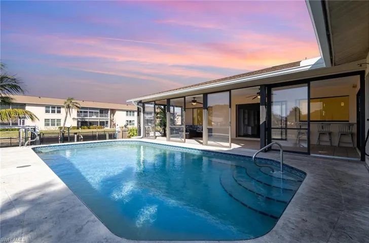 Pool at dusk featuring ceiling fan and a patio