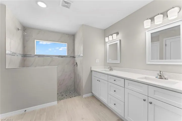 Bathroom with tiled shower and double sink vanity