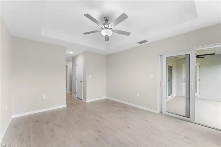 Unfurnished bedroom featuring ceiling fan and a tray ceiling