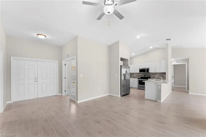 Kitchen with white cabinetry, kitchen peninsula, backsplash, ceiling fan, and stainless steel appliances