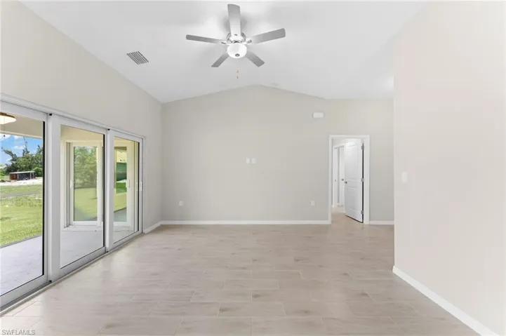 Tiled empty room with vaulted ceiling and ceiling fan