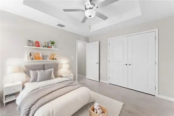 Bedroom with ceiling fan, a closet, and a tray ceiling
