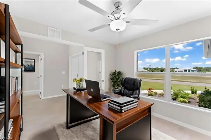 Carpeted office featuring ceiling fan