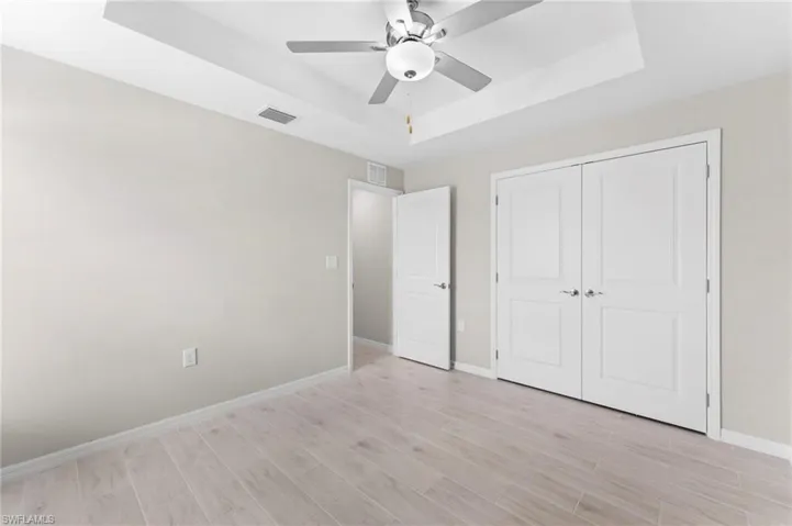 Unfurnished bedroom with a closet, ceiling fan, and a raised ceiling
