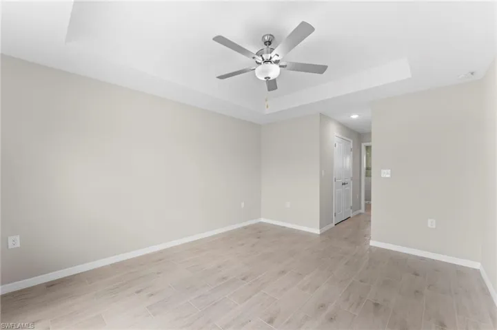 Empty room with ceiling fan and a raised ceiling