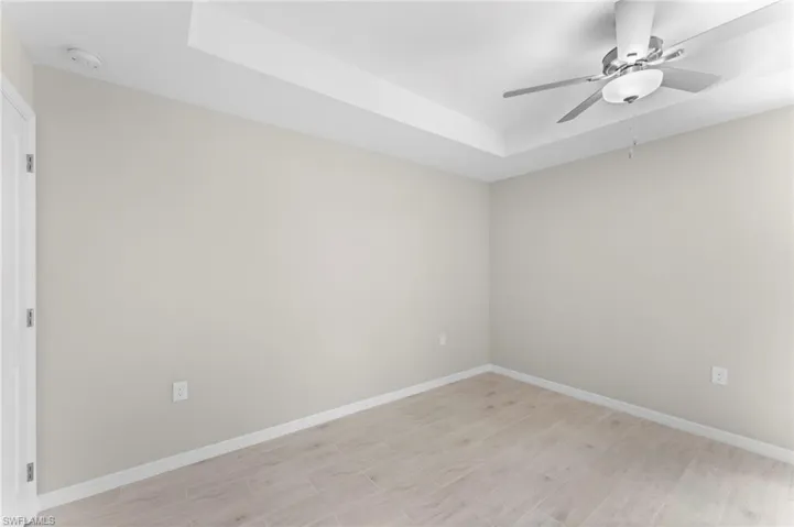 Spare room featuring a tray ceiling, light hardwood / wood-style flooring, and ceiling fan