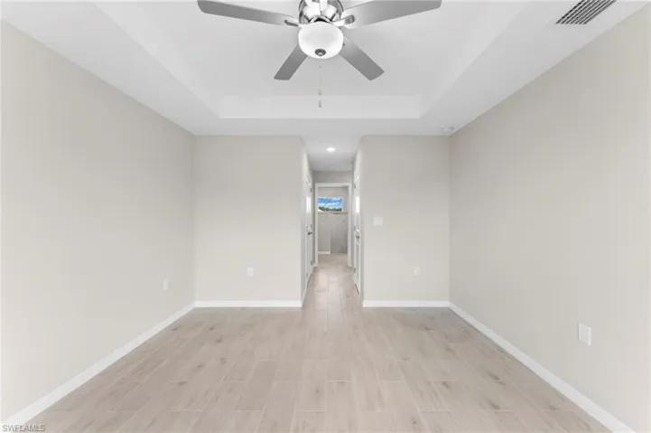 Empty room with ceiling fan and a tray ceiling
