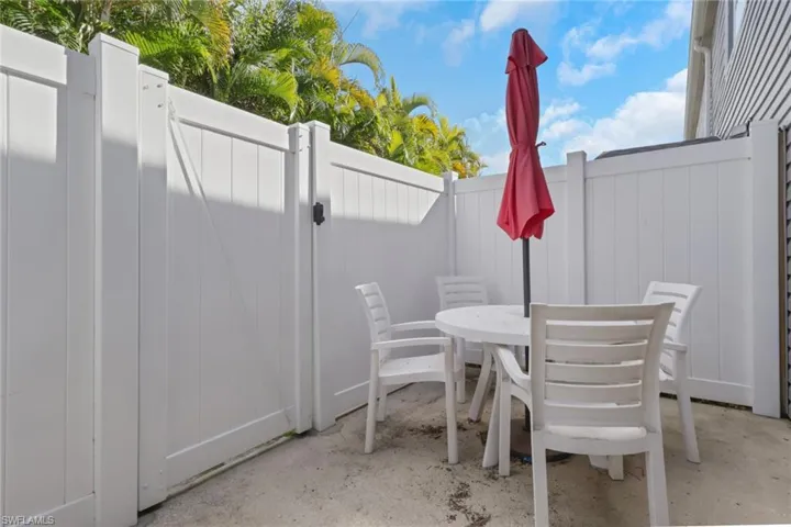 View of patio with outdoor dining space and a gate
