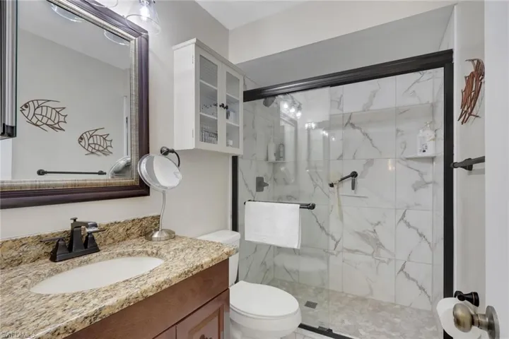Bathroom with a marble finish shower and vanity