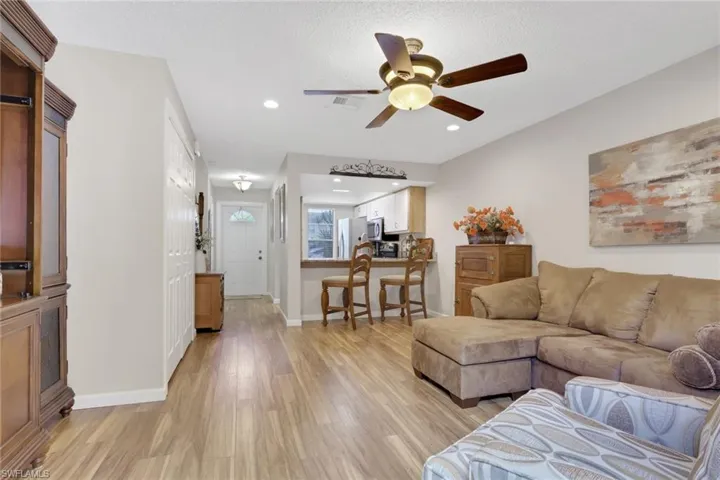 Living area featuring light wood finished floors, ceiling fan, recessed lighting, and a textured ceiling
