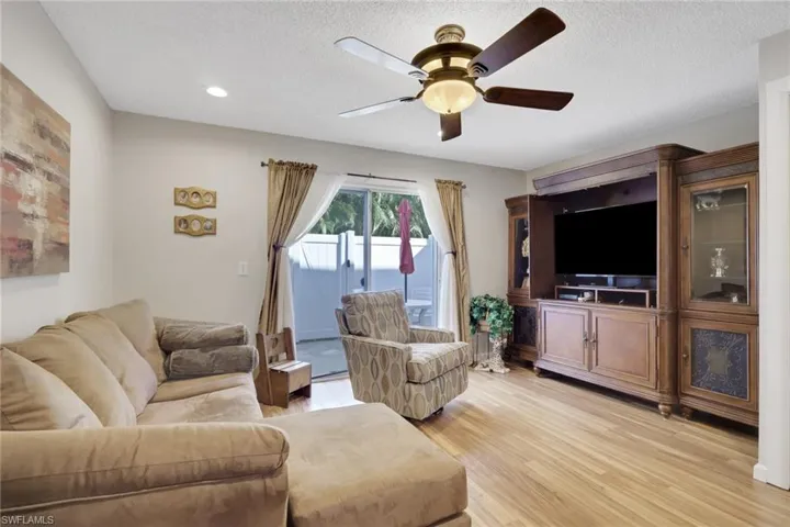 Living area featuring a ceiling fan, light wood finished floors, and a textured ceiling