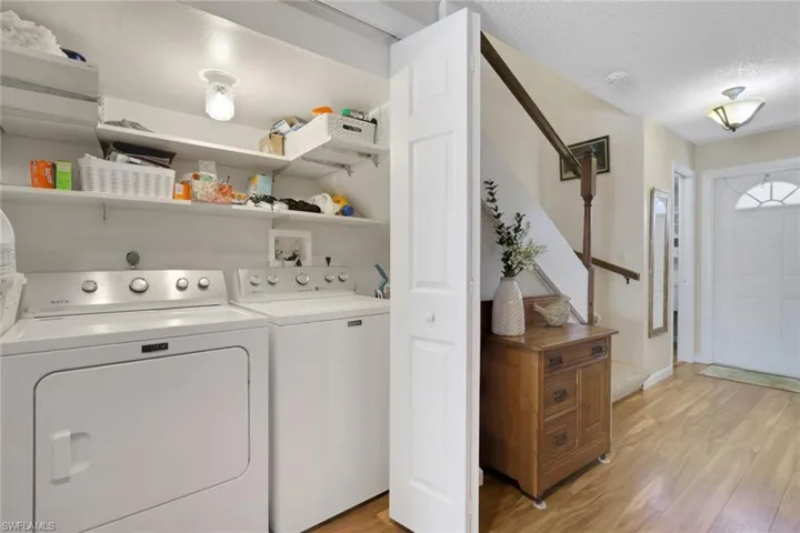 Laundry area with light wood-type flooring, a textured ceiling, and washing machine and dryer