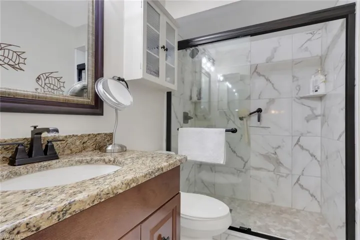 Full bath featuring vanity and a marble finish shower