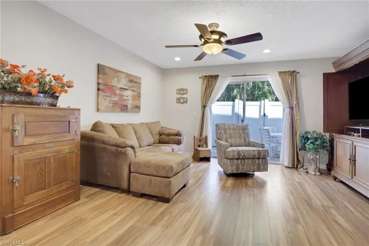 Living area featuring light wood-style floors, ceiling fan, and a textured ceiling